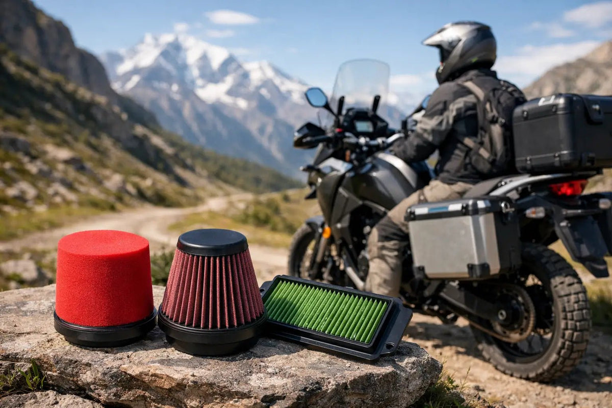 Filtro in spugna, filtro conico in cotone e filtro a pannello appoggiati su una roccia davanti a una moto adventure con valigie