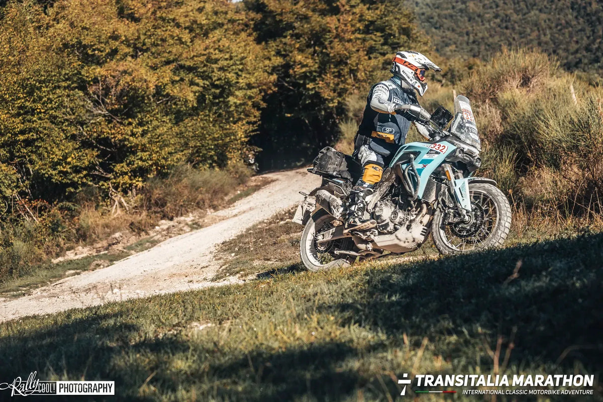 Maxi enduro con numero di gara su una strada bianca dell'Appennino tra boschi autunnali durante il Transitalia Marathon