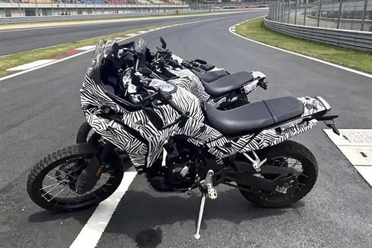 Tre prototipi camuffati della CFMoto 550MT parcheggiati sulla pista di un circuito