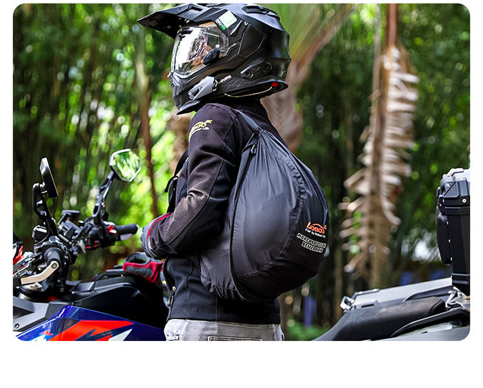 Motociclista con casco adventure accanto alla moto, con la borsa porta casco sulla spalla